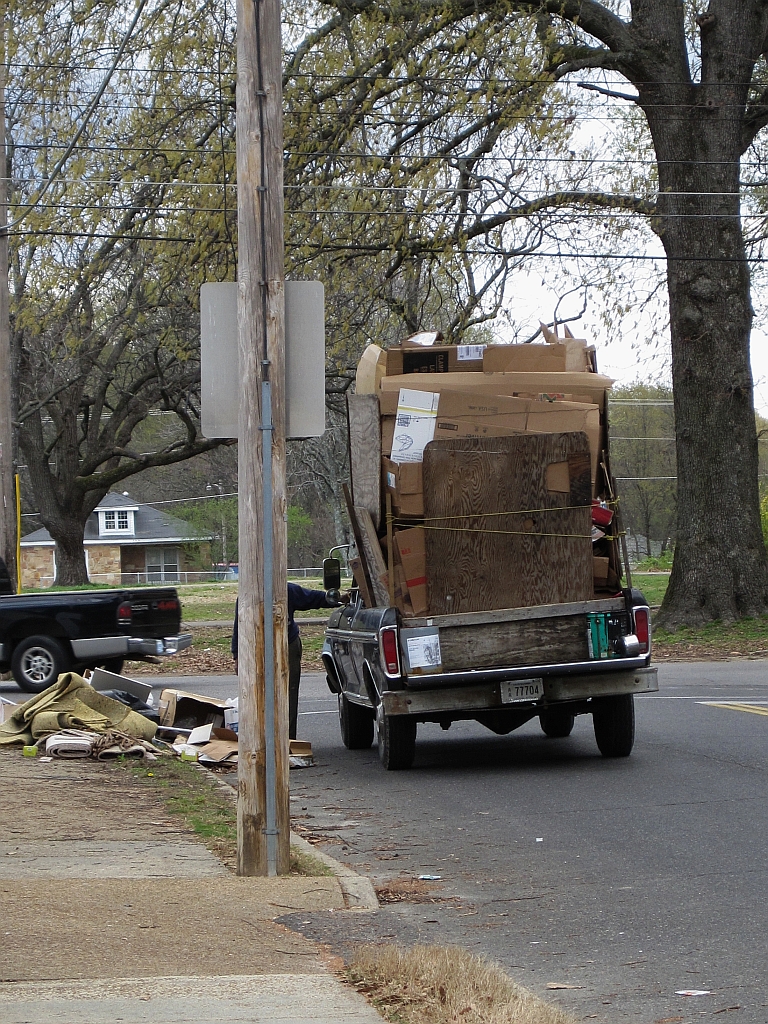 Pickup truck loaded with furniture, mattresses, and household items ready for haul